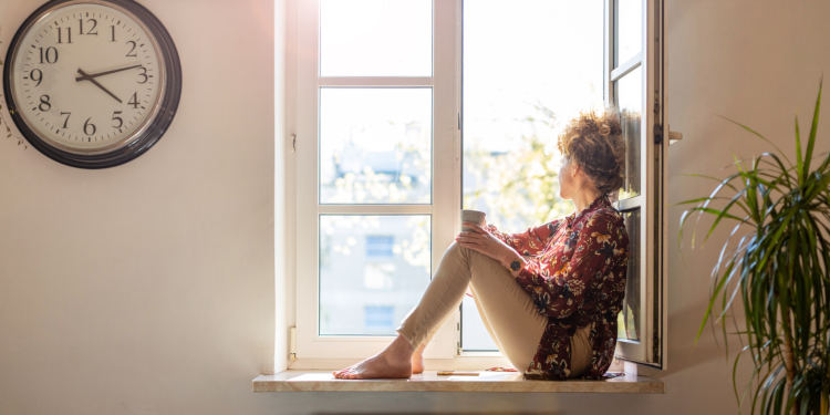 Beautiful young woman sitting at a window sill having rest
